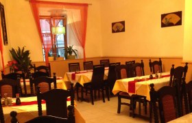 Innenansicht eines asiatischen Restaurants mit gedeckten Tischen und Stühlen.