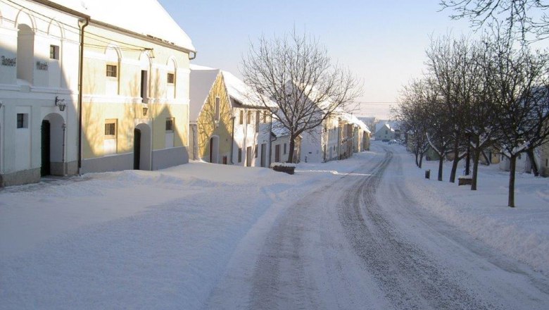 Verschneite Stra&szlig;e mit historischen Geb&auml;uden und B&auml;umen in Straning, &Ouml;sterreich.