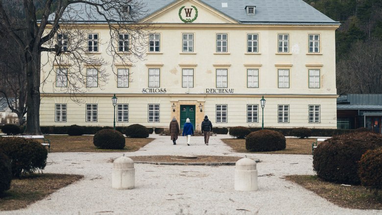 Umgeben von einer malerischen Winterlandschaft, strahlt das Schloss Reichenau eine zeitlose Eleganz aus. Die schneebedeckten Str&auml;ucher und der klare Himmel schaffen eine friedliche Atmosph&auml;re, die zum Verweilen einl&auml;dt. Ein perfekter Ort, um die winterliche Sch&ouml;nheit der Wiener Alpen zu genie&szlig;en.