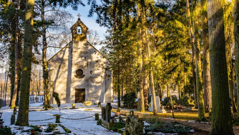 Winterliche Kapelle im Wald mit Gr&auml;bern und Schnee.