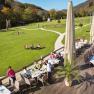 Terrasse des Seminar- und Eventhotels Krainerh&uuml;tte mit G&auml;sten beim Essen, umgeben von gr&uuml;ner Wiese und Wald.
