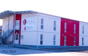 Zweistöckiges Motelgebäude mit rotem und weißem Anstrich, Außentreppe und großem Schild mit der Aufschrift 'Motel'.