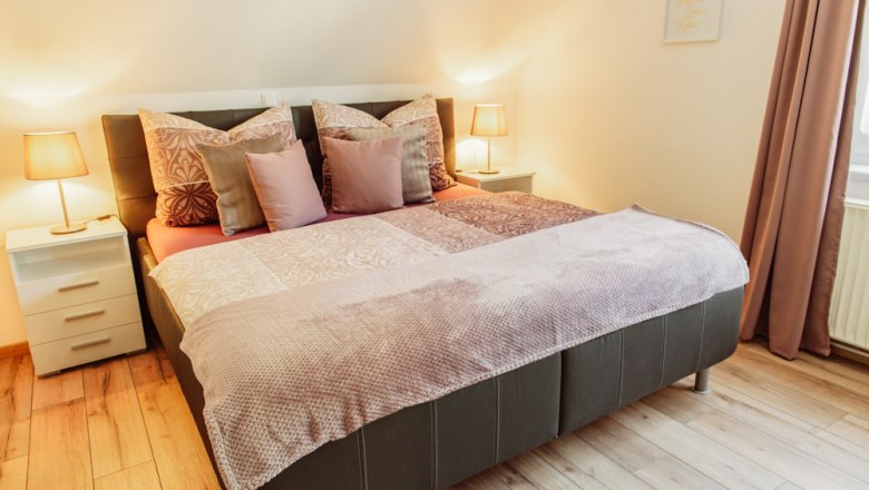 Gemütliches Schlafzimmer mit Doppelbett, Nachttischen und Lampen.