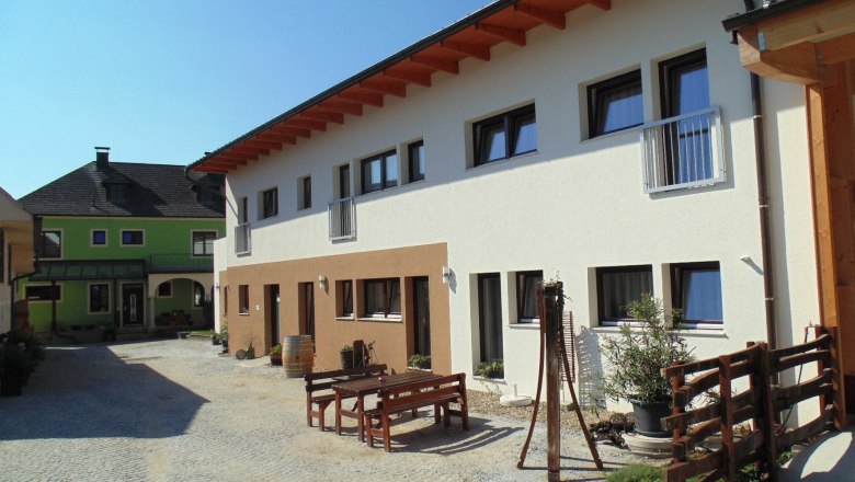 Innenhof mit modernen Geb&auml;uden und Holzm&ouml;beln im Freien.