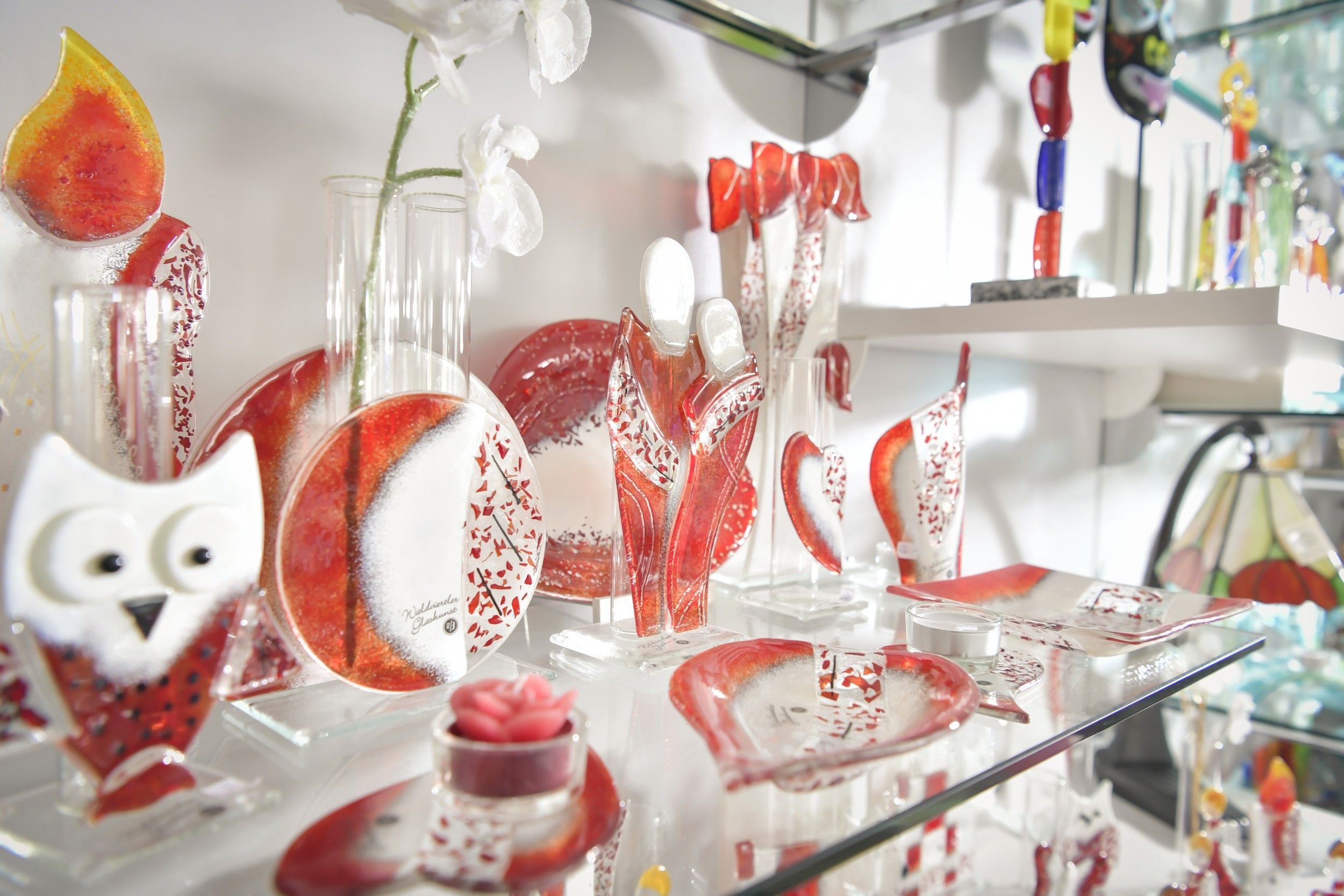 Glasdekorationen in Rot und Weiß auf einem Regal.