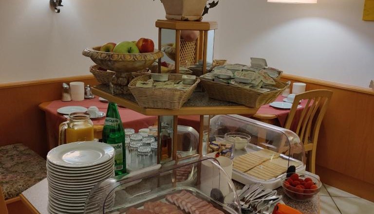 Frühstücksbuffet mit Aufschnitt, Käse, Obst und Getränken.