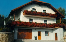 Ein traditionelles Gästehaus mit roten Blumen auf den Balkonen und einem roten Dach.