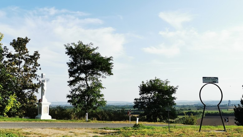 Landschaft mit Kreuz und Seefeld-Kadolz Schild.