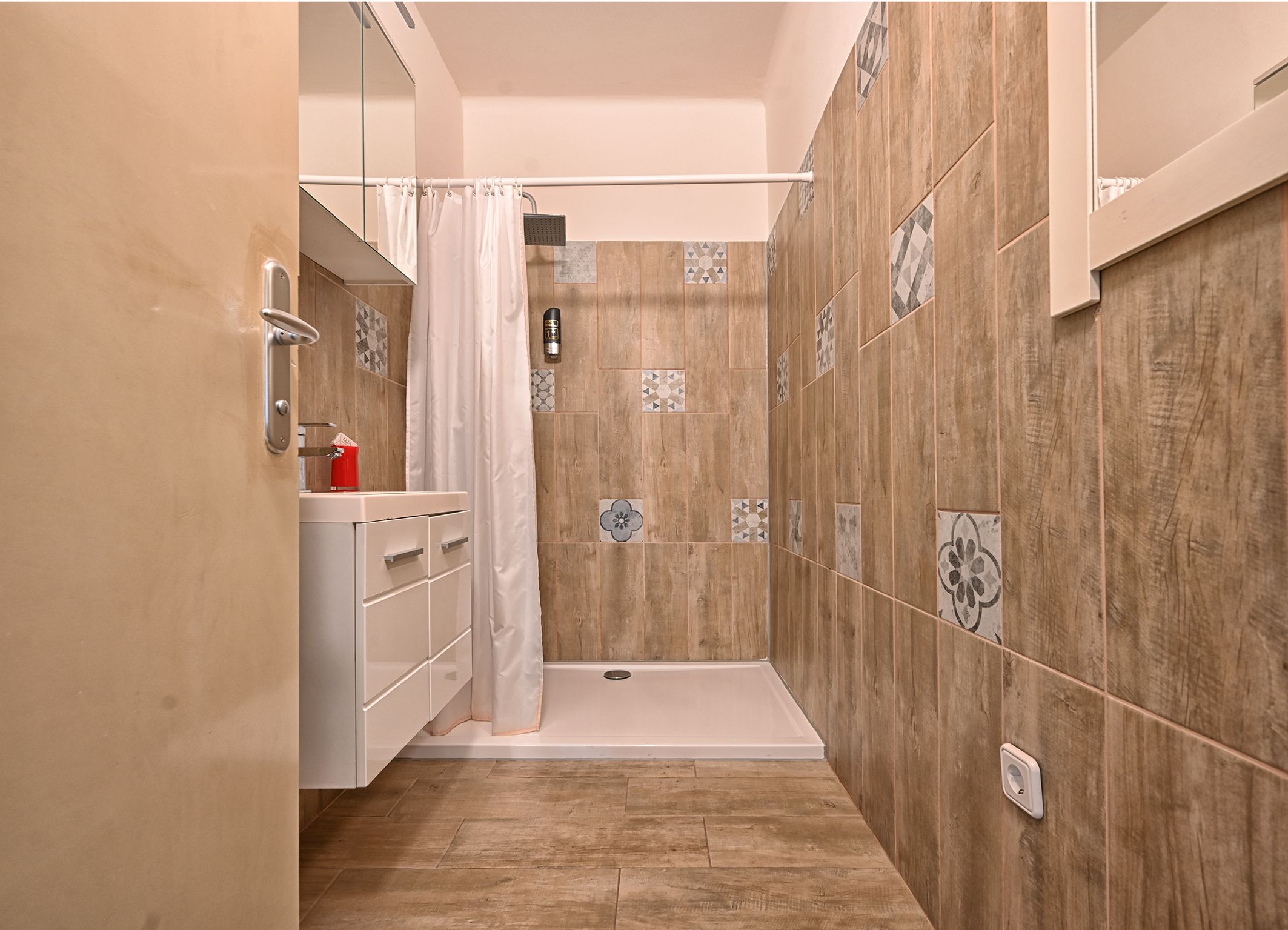 Modernes Badezimmer mit Duschkabine, Fliesenwänden und Waschtisch.