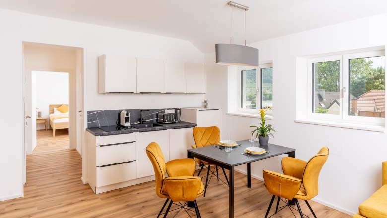 Moderne Küche mit Esstisch und gelben Stühlen in einer Ferienwohnung.