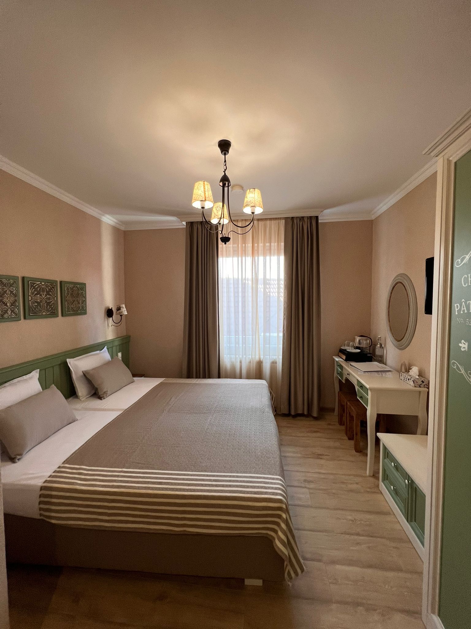 Gemütliches Hotelzimmer mit Doppelbett, Schreibtisch und Fenster mit Vorhängen.