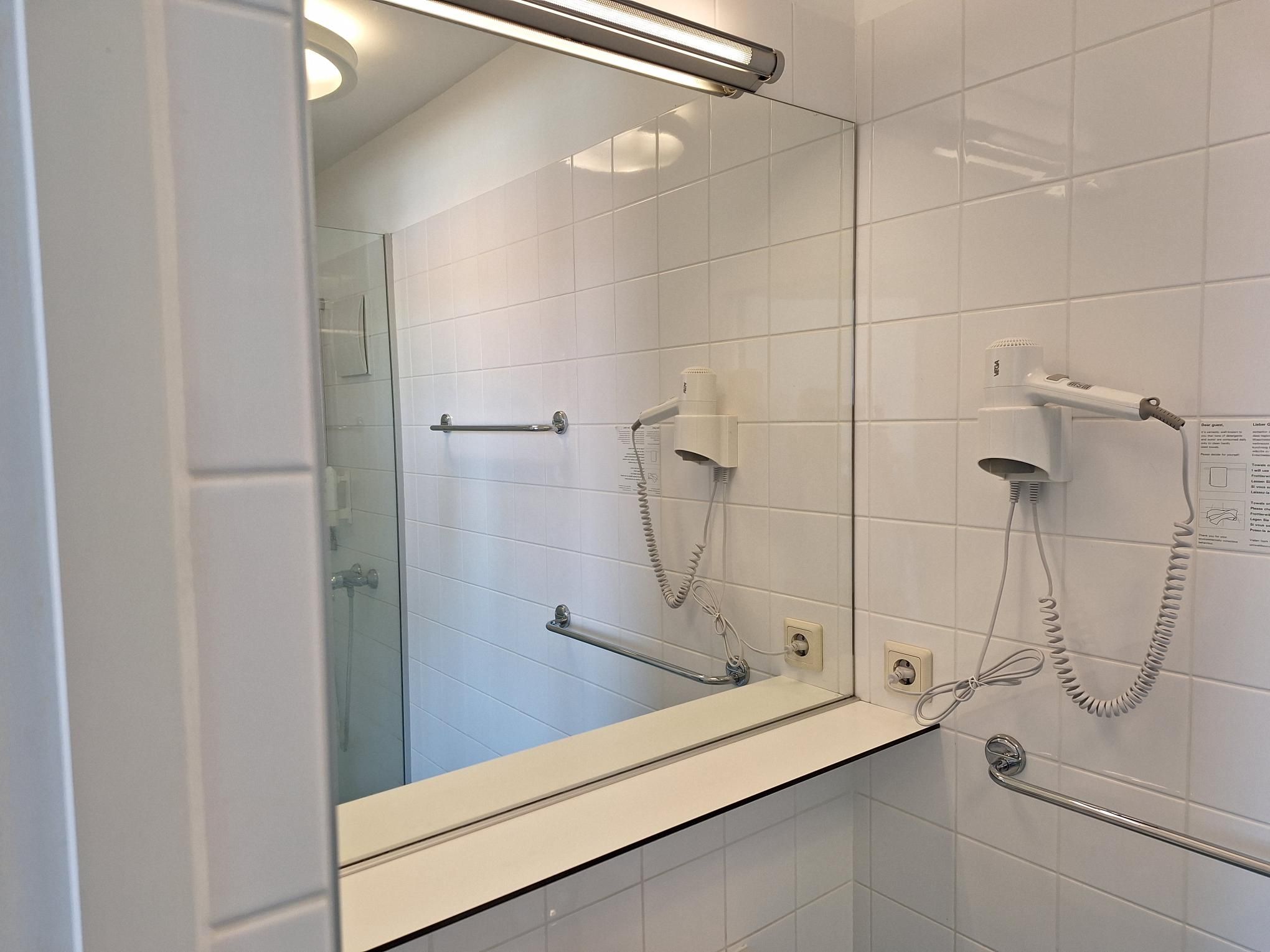 Modernes Badezimmer mit Spiegel, Haartrockner und Handtuchhalter.