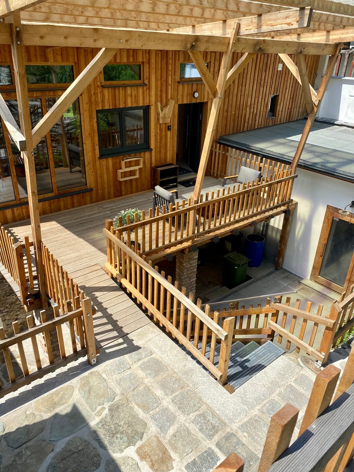 Holzterrasse mit Geländer und angrenzendem Gartenbereich.