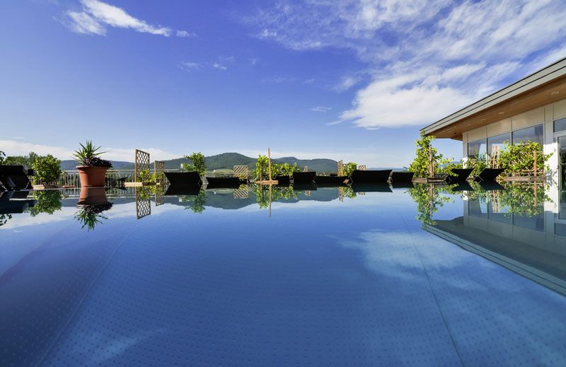 Ein moderner Pool auf einem Penthouse mit Blick auf Berge und blauen Himmel.