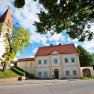 Pfarrhof Zuschmann mit Kirche und blauem Himmel.