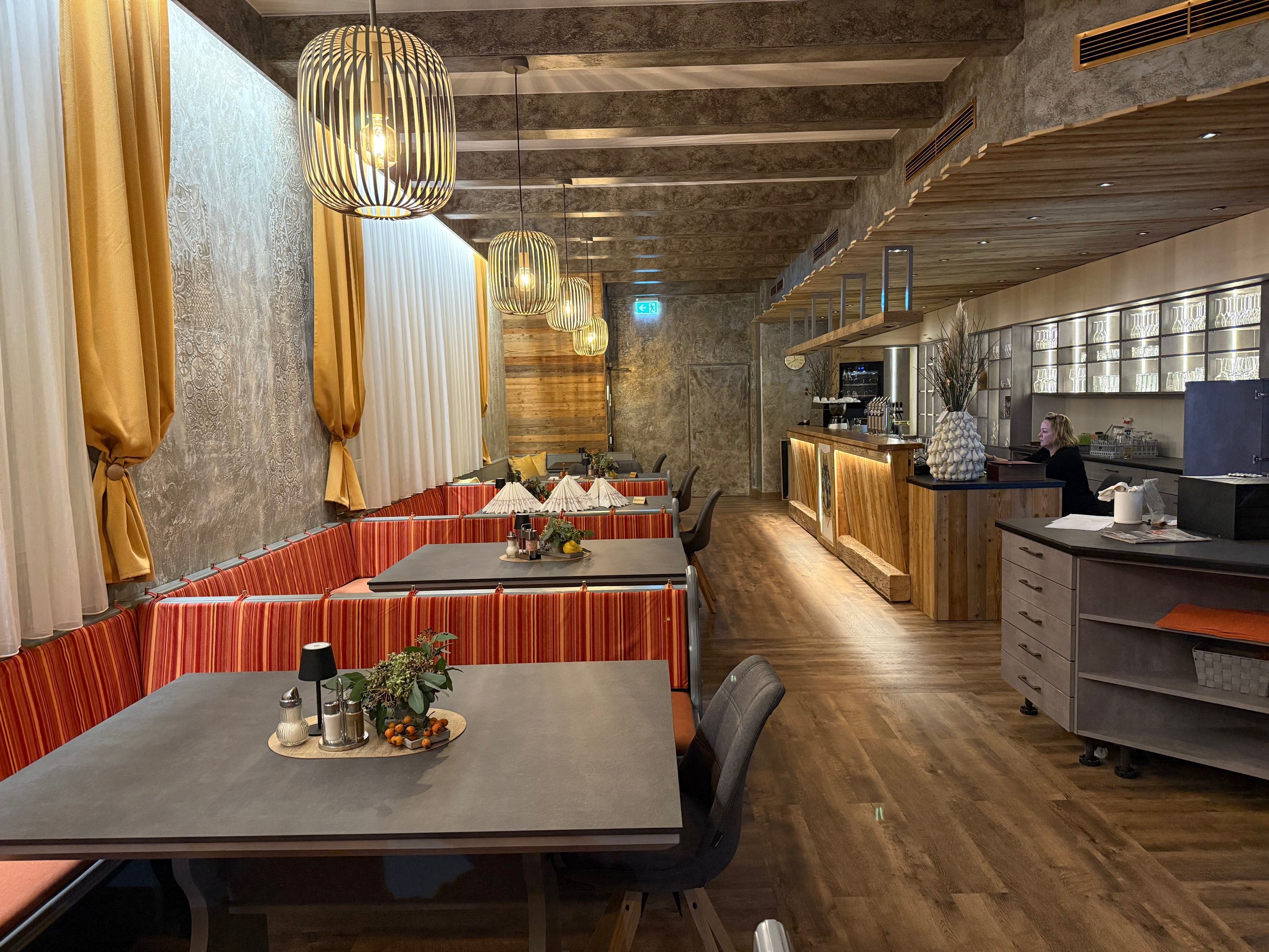 Innenansicht eines stilvollen Restaurants mit Holzelementen und moderner Beleuchtung.