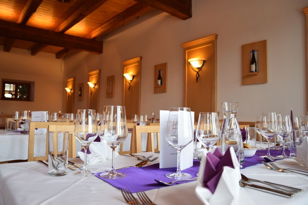 Elegantes Restaurant mit gedeckten Tischen, Weingläsern und lila Servietten.