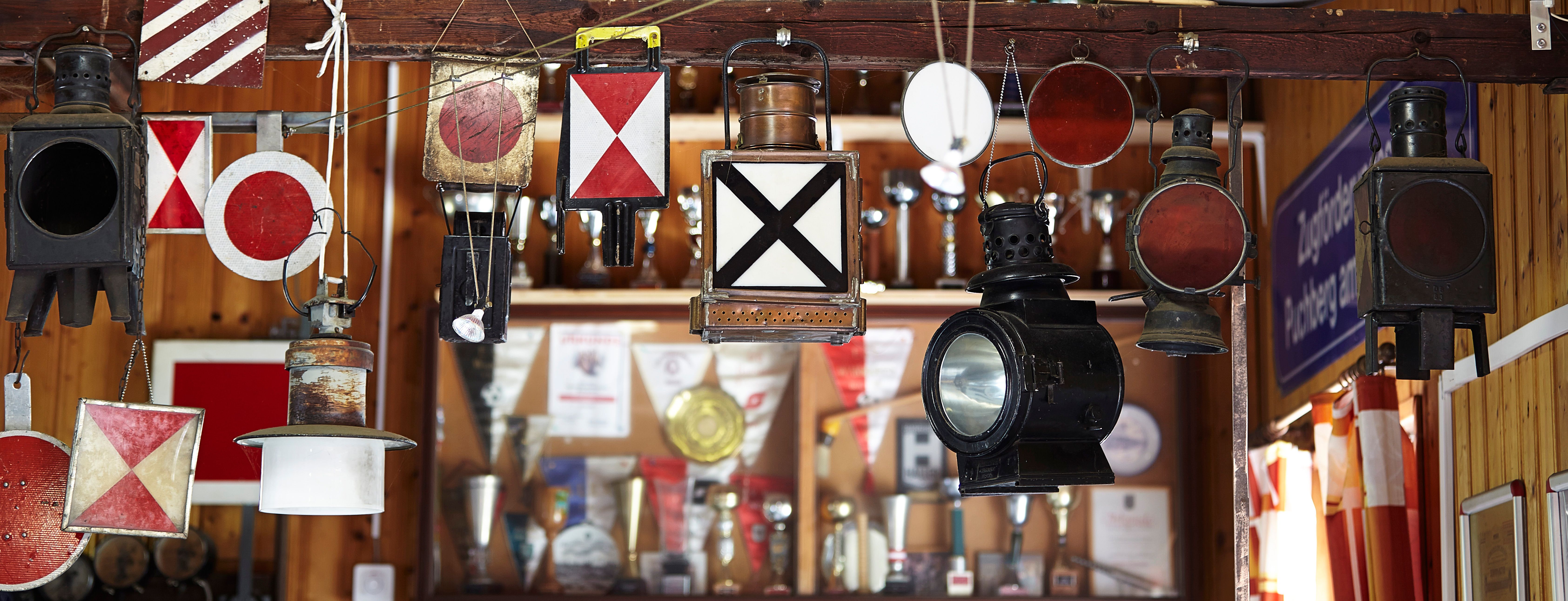 Verschiedene alte Eisenbahnlampen und Signale hängen in einer Ausstellung.