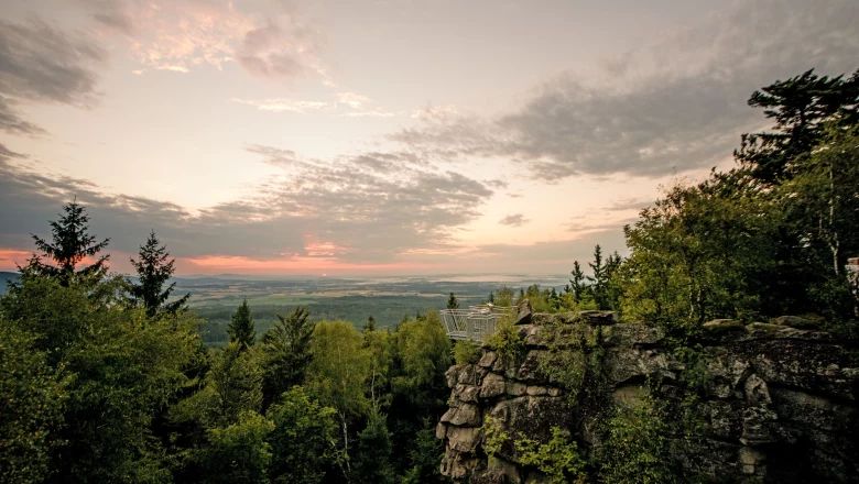 Aussichtspunkt Mandelstein mit Blick auf bewaldete Landschaft bei Sonnenuntergang.