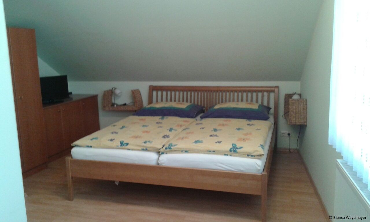 Ein Schlafzimmer mit einem Doppelbett, einem Schrank und einem Fernseher auf einem Schrank.