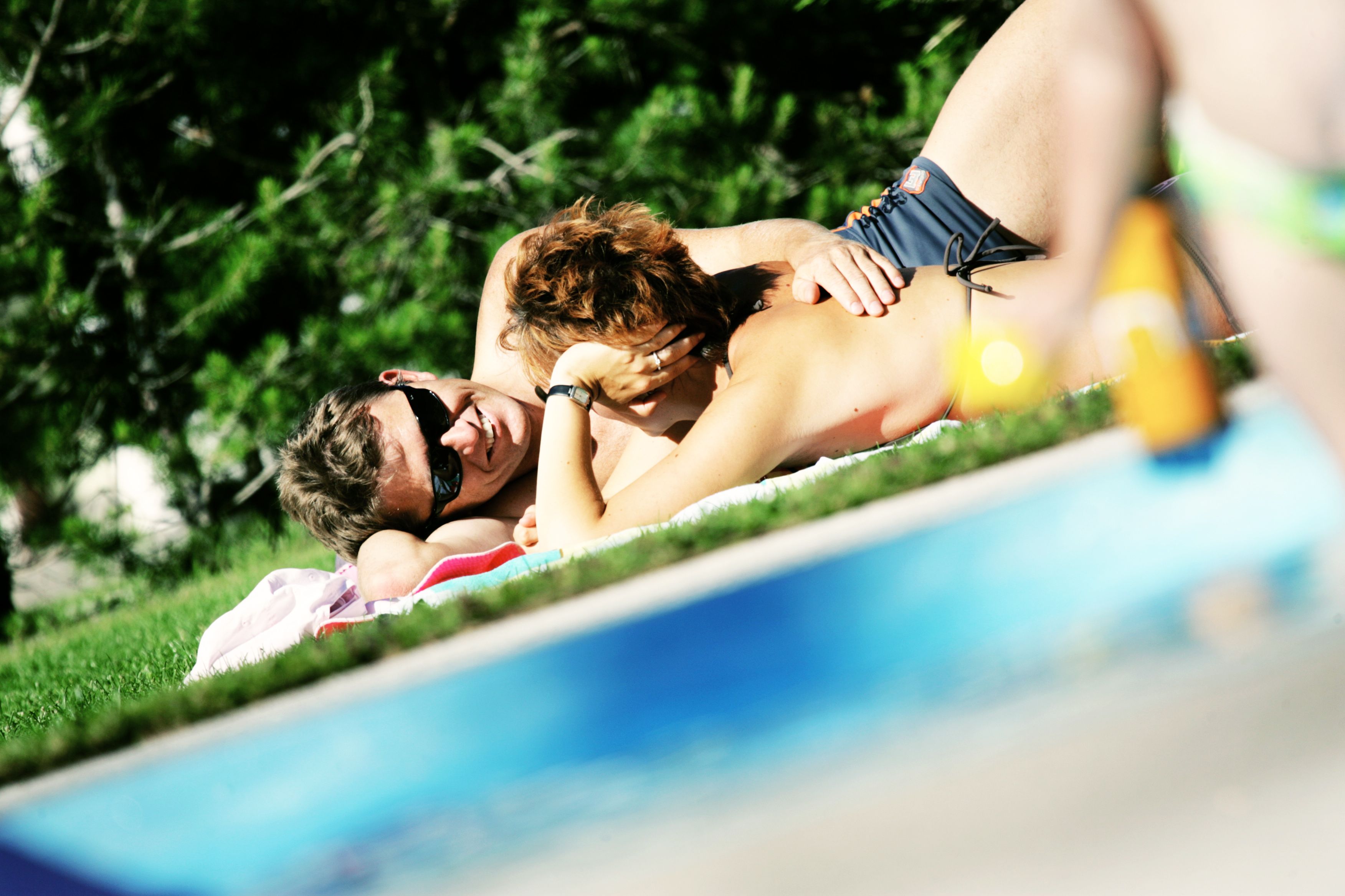 Ein Paar liegt entspannt auf einer Wiese am Pool im Freibad Mitterbach.