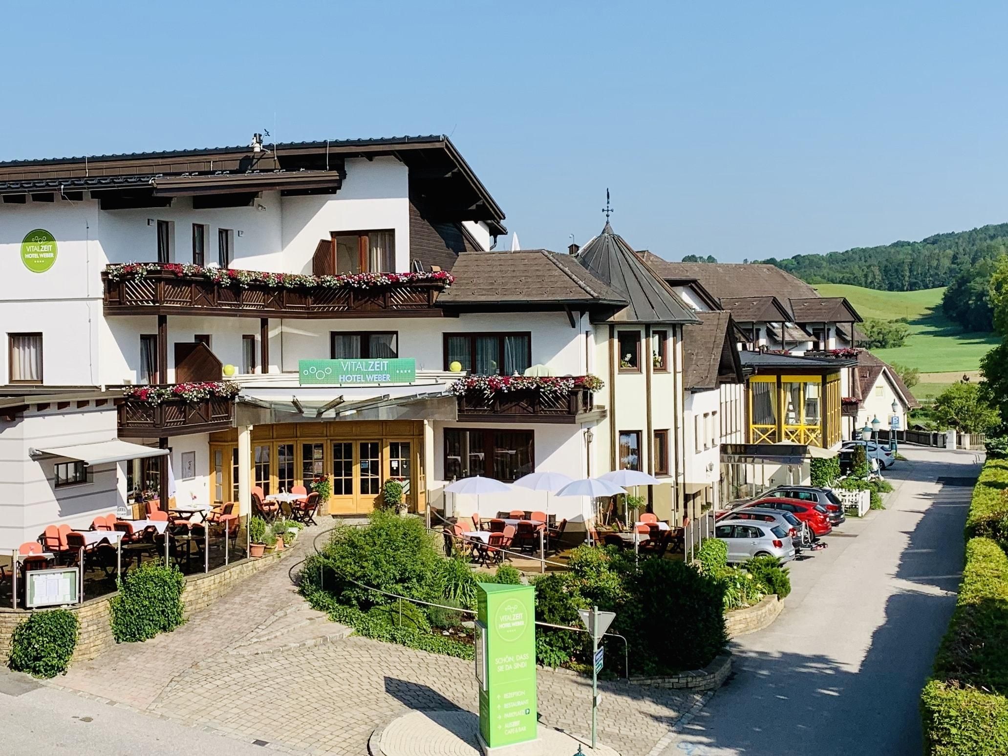 Außenansicht des VitalZeit Hotel Weber mit Terrasse und umliegender Landschaft.