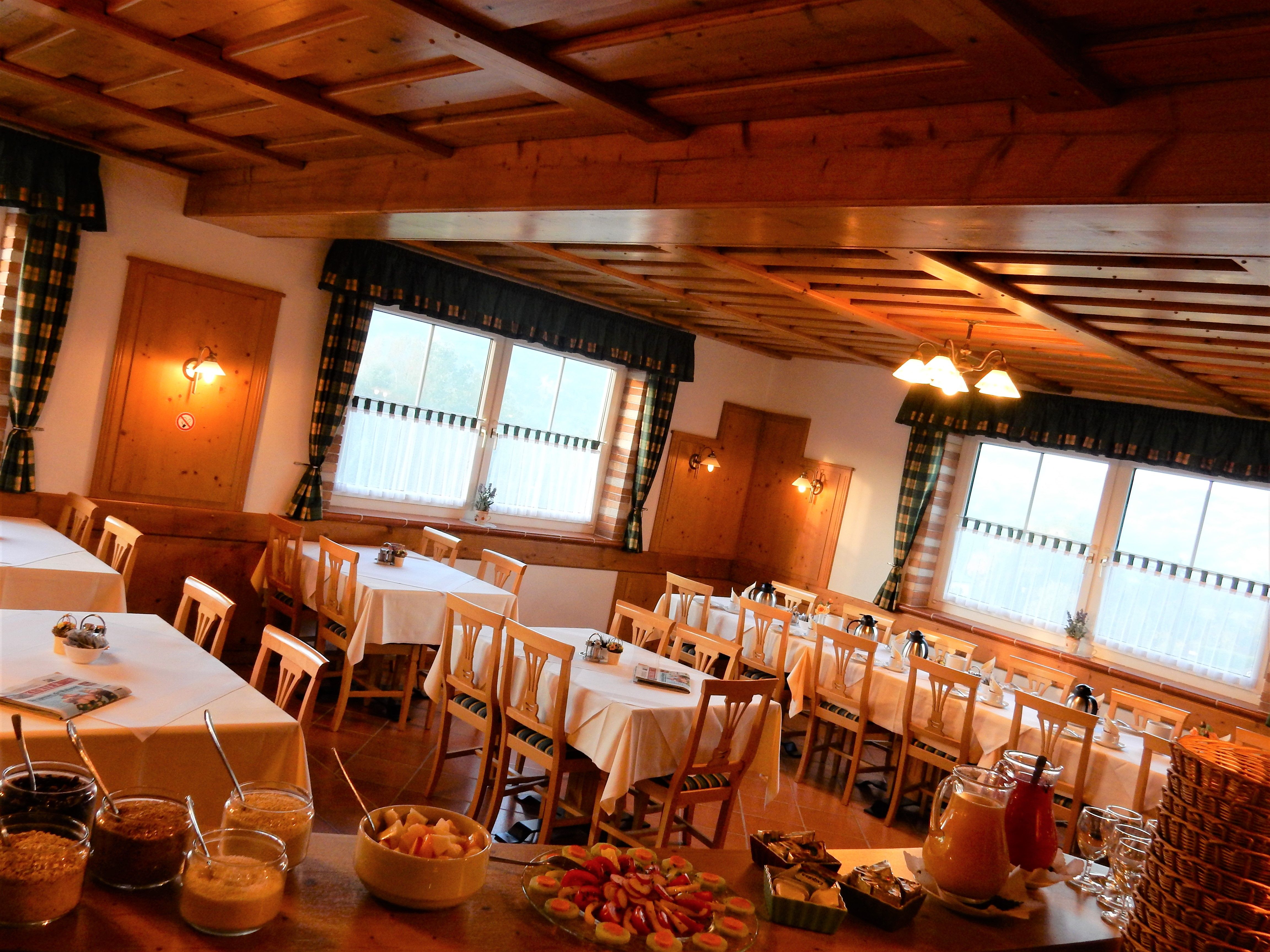 Gemütlicher Frühstücksraum mit Holzmöbeln und gedeckten Tischen.