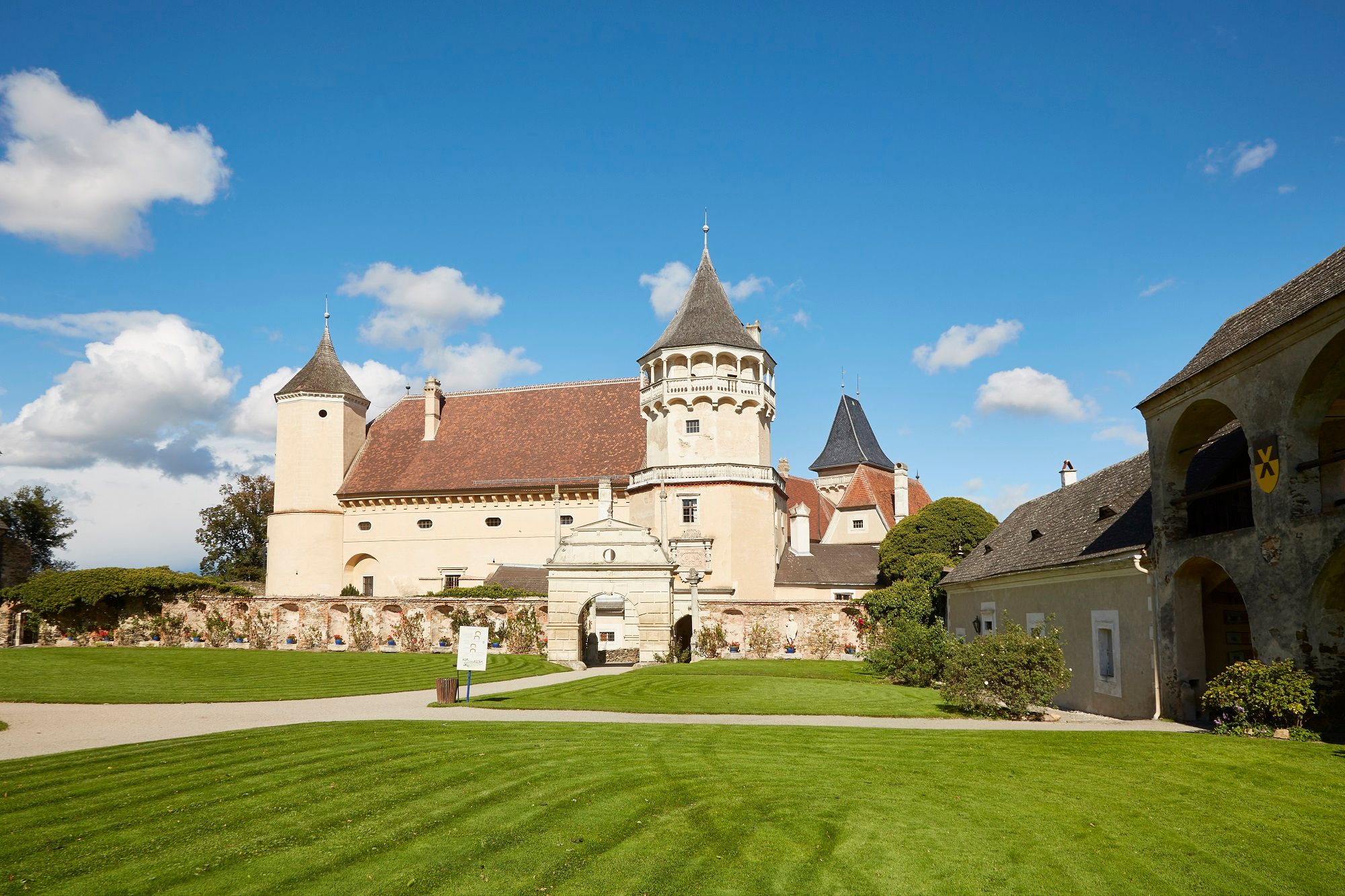 Schloss Rosenburg mit Türmen und gepflegtem Rasen unter blauem Himmel.
