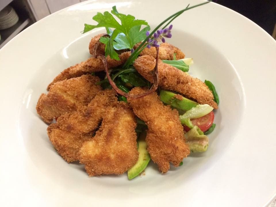 Ein Teller mit Salat und Gebackenem, garniert mit Kräutern.