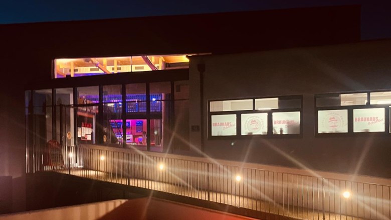 Nachtaufnahme Brauhaus Schwechat mit beleuchteten Fenstern und farbigen Kugelleuchten im Vordergrund.