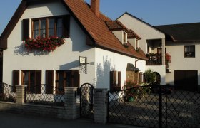 Ein zweistöckiges Haus mit weißen Wänden, roten Dachziegeln und Blumenkästen vor den Fenstern.