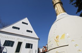 Weinkeller Max Riegelhofer und gro&szlig;e Sektflasche im Freien.