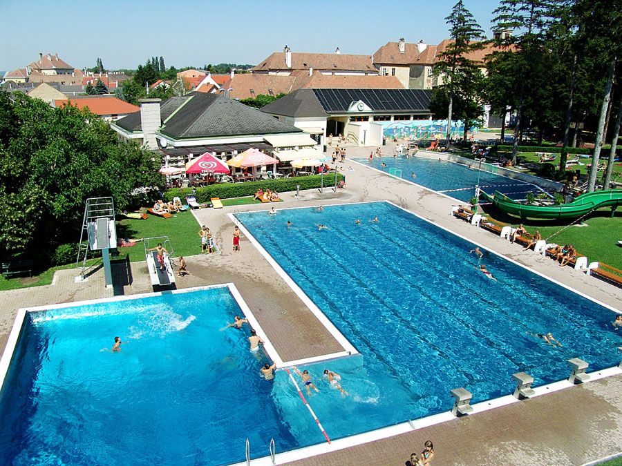 Luftaufnahme eines Freibads mit mehreren Schwimmbecken und einer Rutsche.