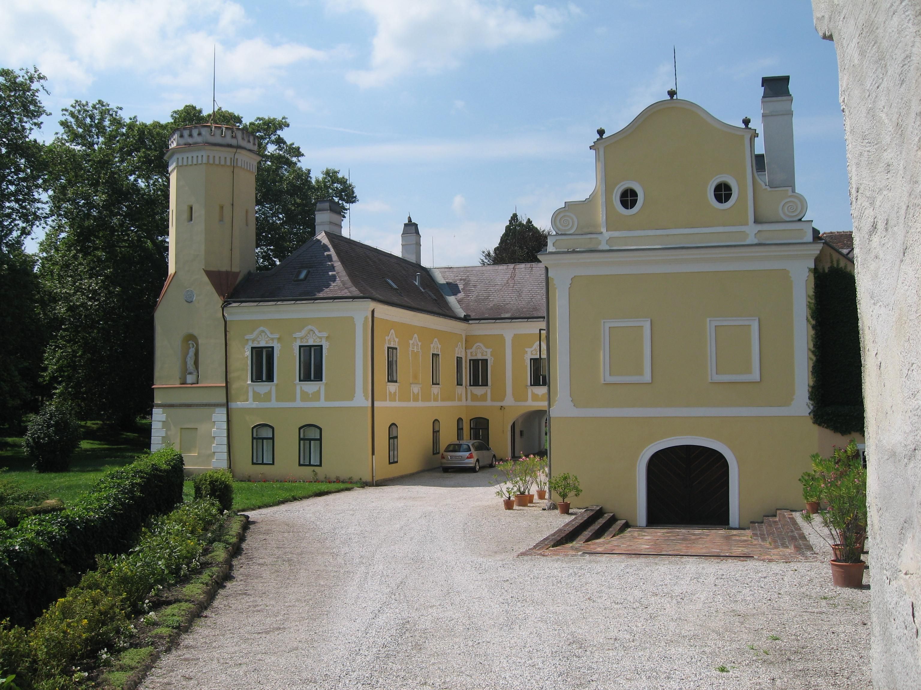 Gelbes Schloss mit Turm und Garten.