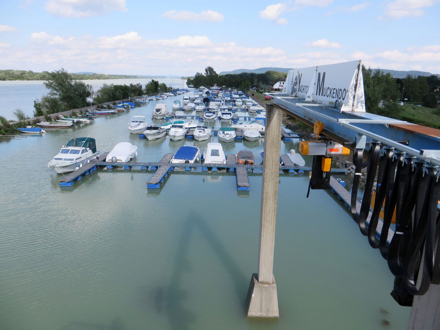 Yachtclub Muckendorf mit vielen Booten am Steg und einem Kran im Vordergrund.