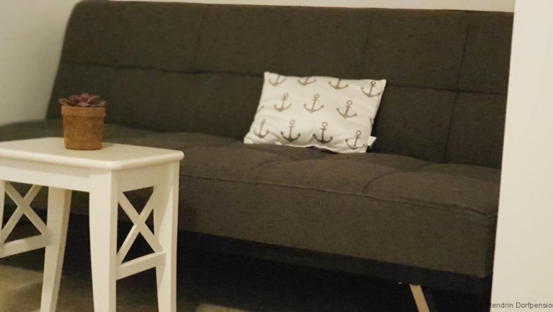 Graues Sitzsofa mit weißem Tisch.