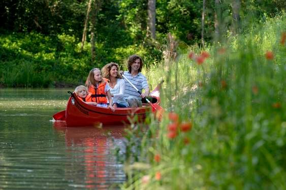 Familie im Kanu auf einem Fluss im Grünen.