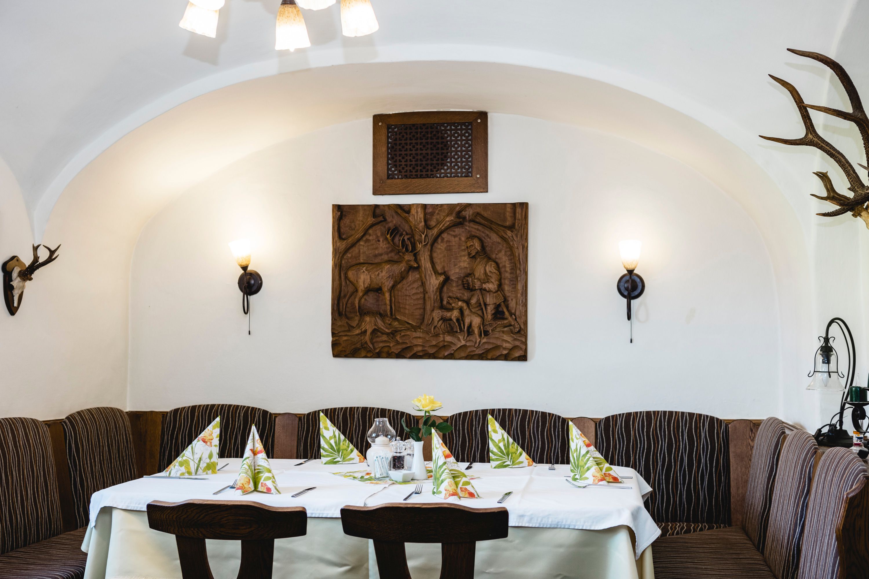 Gemütlicher Gastraum mit Holztäfelung und Jagdmotiven an der Wand.