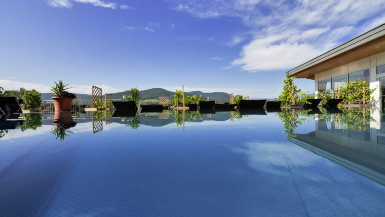 Ein moderner Pool auf einem Penthouse mit Blick auf Berge und blauen Himmel.