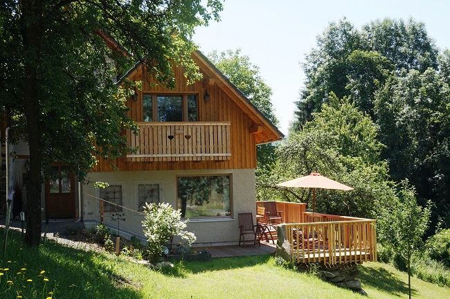 Ein gemütliches Holzhaus mit Balkon und Terrasse inmitten grüner Natur.