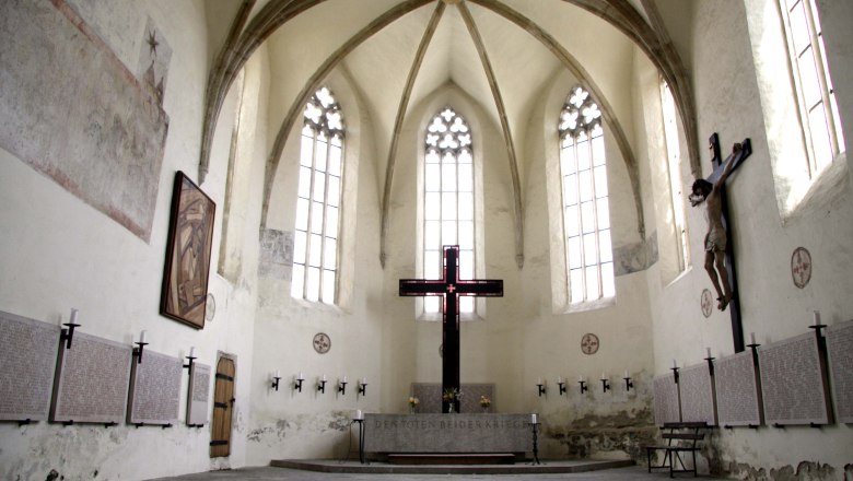 Innenansicht der Frauenbergkirche Stein mit gotischen Fenstern und einem großen Kreuz.