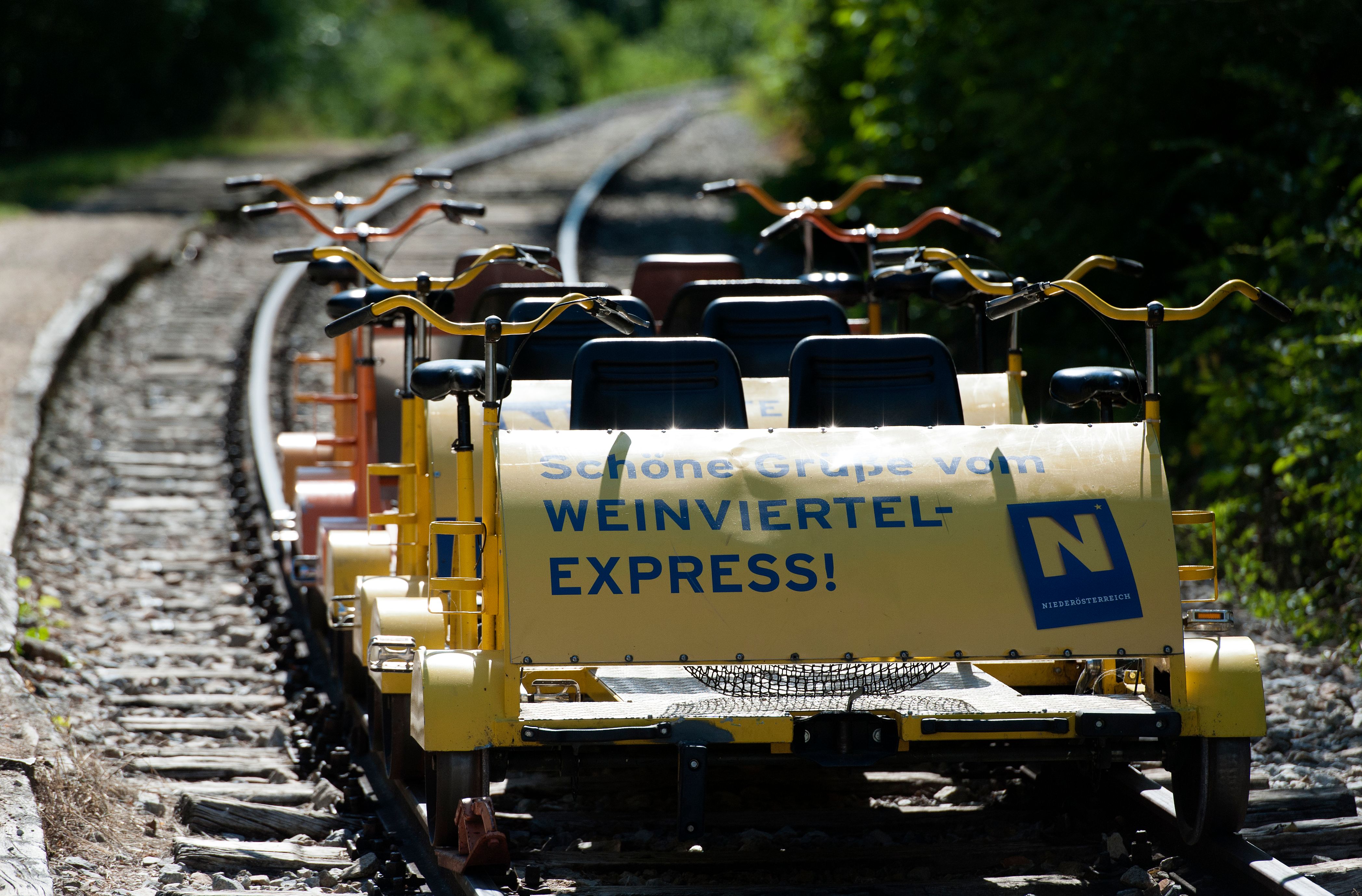 Gelbe Draisine auf Schienen mit der Aufschrift 'Weinviertel-Express'.