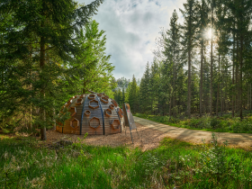 Umgeben von majestätischen Bäumen und sanften Hügeln, lädt die Moorkugel zu einer Auszeit in der Natur ein. Die harmonische Verbindung von Holz und Natur schafft eine einladende Atmosphäre, die Wanderer und Naturliebhaber gleichermaßen begeistert.