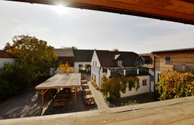 Innenhof eines Weinguts mit Holzbauten und Weinreben.