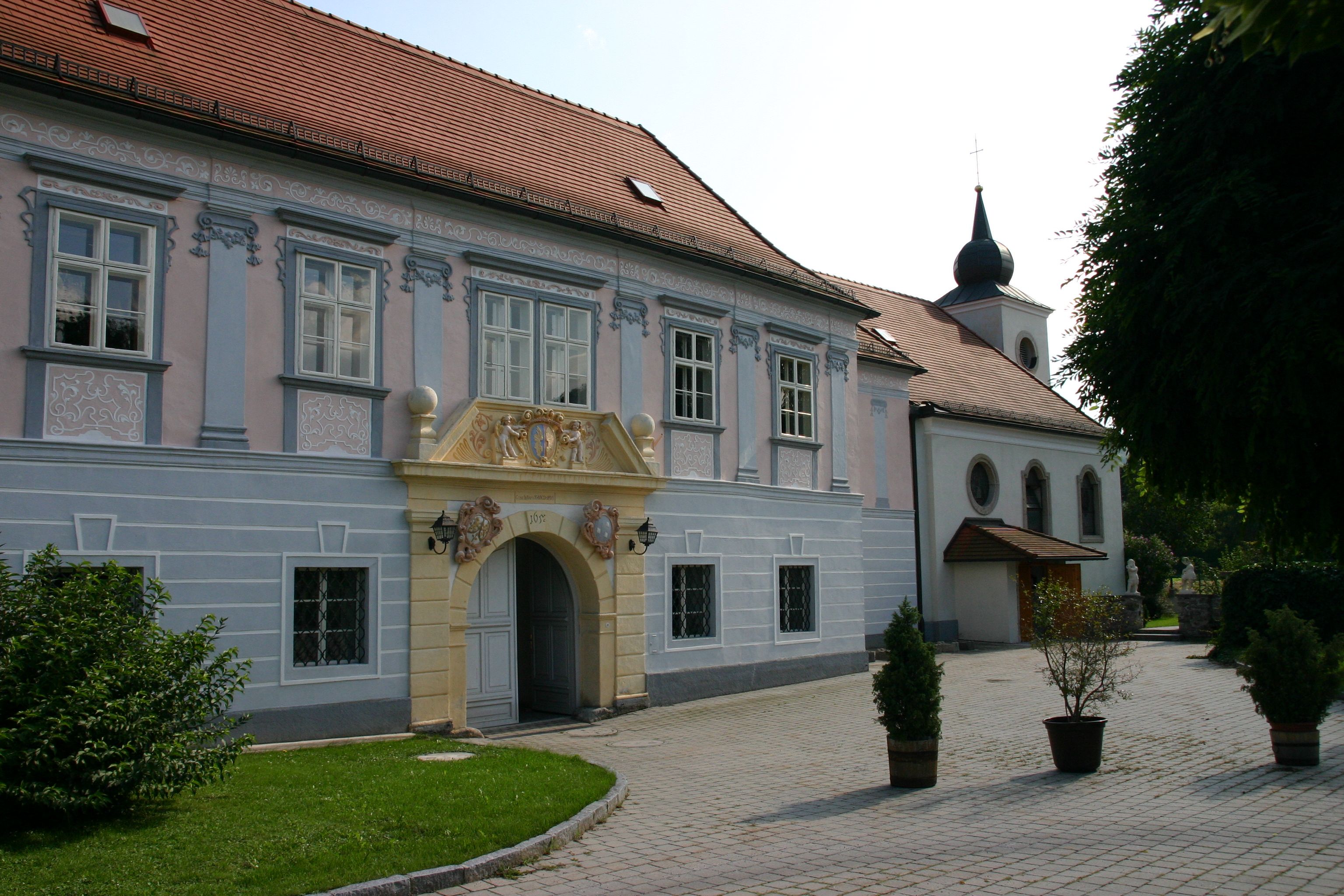 Historisches Gebäude mit verziertem Eingang und Kirche im Hintergrund.
