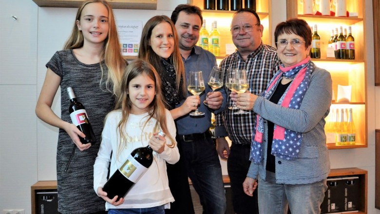 Familie mit Weinflaschen und Gläsern in einem Weinkeller.