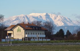 Gebäude mit der Aufschrift 'mattone apartments' vor schneebedecktem Berg im Hintergrund.
