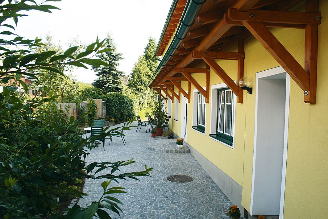 Gepflasterter Hof mit gelbem Gebäude und Gartenmöbeln.