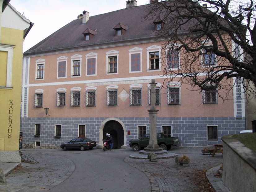 Schloss Rossatz mit gepflastertem Vorplatz und einem Baum im Vordergrund.