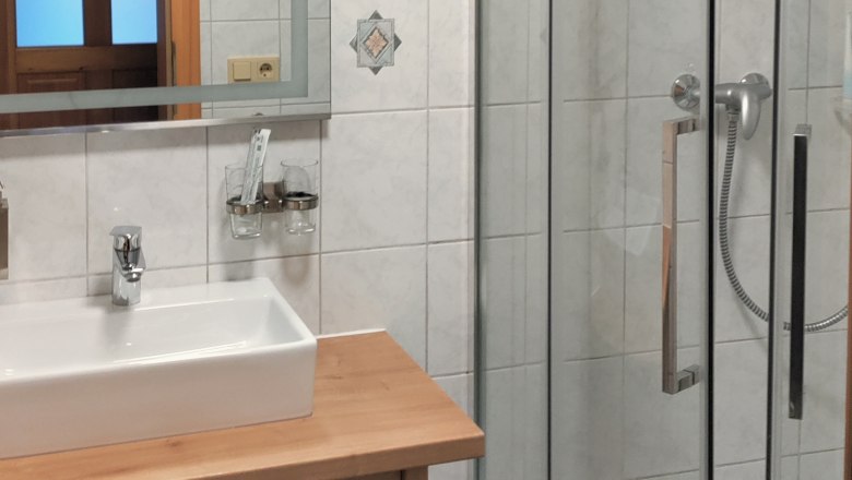 Modernes Badezimmer mit Dusche, Waschbecken und Spiegel.